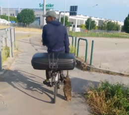 In bicicletta con una nutria in mano