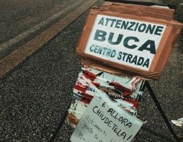 Ironia e polemiche sui cartelli copri-buca